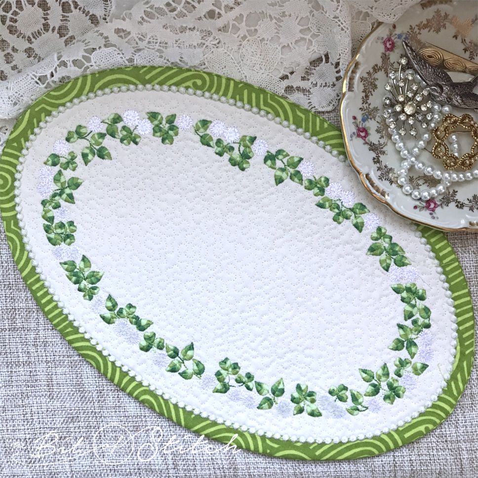 "Rolling in Clover" machine embroidery designs by A Bit of Stitch. Clover flower vine wreath design on MITH oval shaped coaster