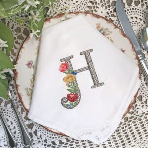 Fiori Script machine embroidery design by A Bit of Stitch - Elegant lacy floral H monogram on dinner napkin
