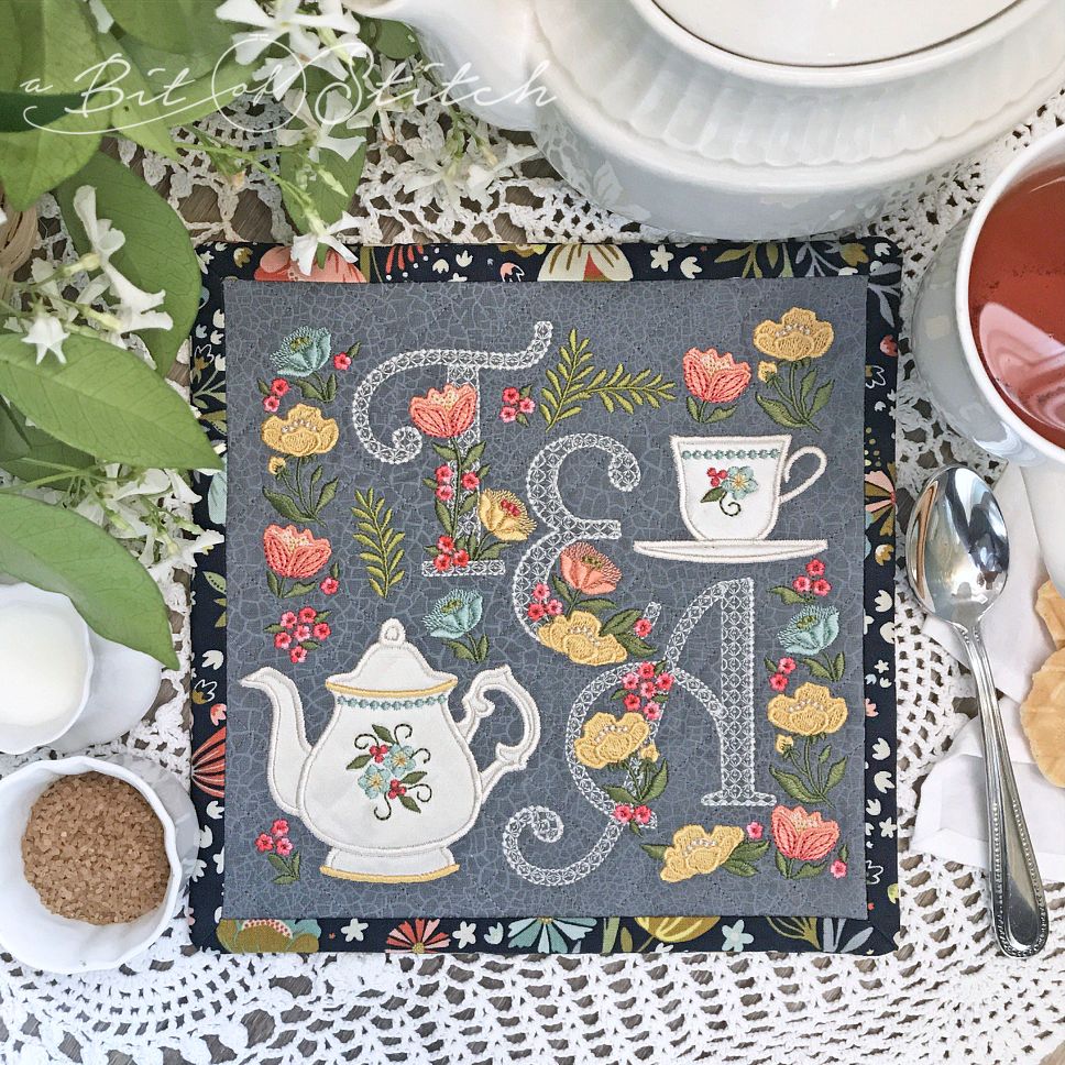 Tea mat with lacy floral script letters, elegant flowers embroidery, and applique teapot and teacup - machine embroidery designs by A Bit of Stitch